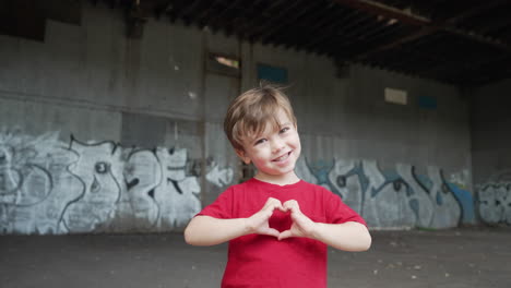 A-young-little-boy-is-having-fun-and-making-heart-symbols-with-hands-in-front-of-camera-in-a-red-T-shirt