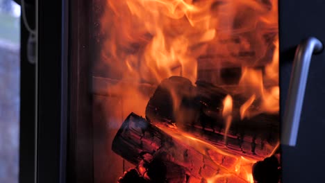 Side-shot-of-domestic-home-indoor-fireplace-with-bed-of-red-hot-timber-wood-as-orange-flames-fly-upwards-in-slow-motion