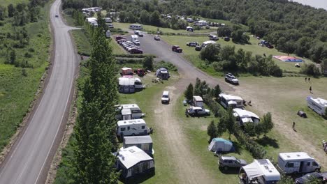 Camping-site-Hallormsstaður-in-east-Iceland-on-sunny-day,-parked-vehicles,-aerial