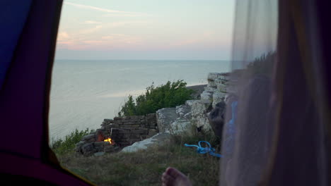 Looking-out-from-tent-at-popular-tourist-camping-spot-location-Sweden-visit-tourism-German-camper-hiking-driving-caravan-to-fireplace-having-good-time-sunset-view-over-night-cozy-hipster-lazy-days-bbq