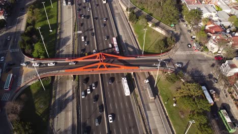 Aerial-top-down-shot-of-cars-driving-on-Pan-American-Highway-under-red-bridge-in-Buenos-Aires