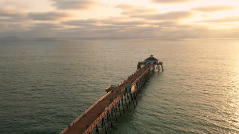 Drone-slowly-orbits-above-Imperial-Beach-Pier-at-sunset-with-people-fishing
