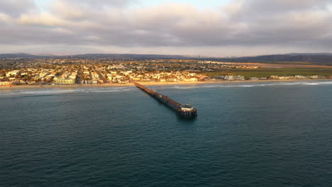Aerial-drone-wide-shot-Imperial-Beach-Pier-with-Tijuana-Mexico-skyline-in-the-distance
