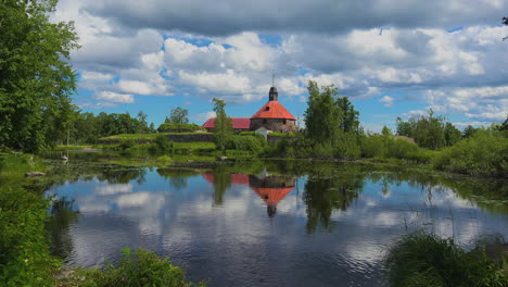 A-wide-view-of-Green-foliage-with-a-lake-reflecting-the-whole-picture-in-the-water-giving-a-heavenly-view-at-Museum-fortress-korela,-Russia
