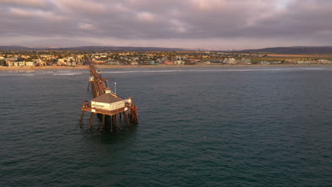 Drone-over-water,-slowly-orbiting-around-front-of-Imperial-Beach-Pier