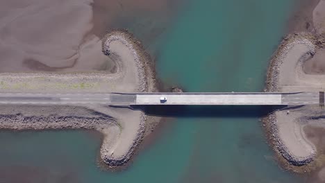 Car-driving-over-bridge-in-east-Iceland-at-Breiðdalsvík-fjord,-top-down