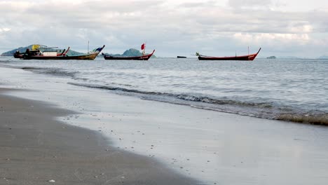 Barcos-De-Pesca-Amarrados-A-Lo-Largo-De-Una-Playa-Azotada-Por-El-Viento-Durante-El-Día-En-El-Sur-De-Tailandia