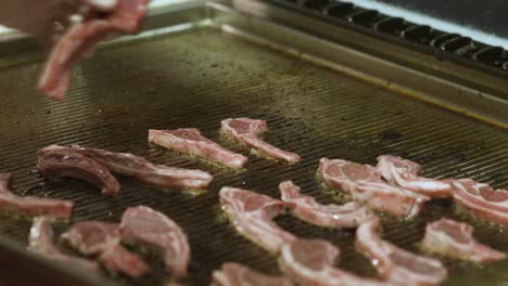 Close-up-of-placing-raw-pork-chops-on-a-restaurant-grill