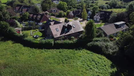 A-high-flying-and-static-drone-tripod-shot-of-large-and-expensive-houses-in-the-middle-of-the-countryside-in-an-unpopulated-town-in-the-cotswolds-in-england-on-a-very-sunny-and-cloudless-day-o