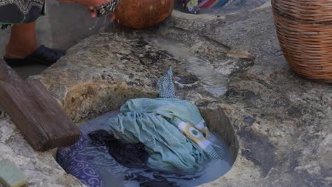 Close-up-of-a-woman-using-a-traditional-stone-trough-to-wash-clothing-like-in-the-1900s-during-a-historical-re-enactment-in-Kritou-Terra,-Greece