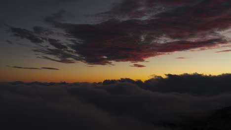 Sunlight-coloring-clouds-above-sea-of-mist-rolling-over-mountains-in-Madeira,-timelapse