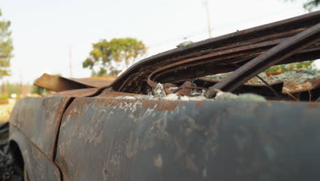 Close-up-view-of-a-useless-crashed-rusty-abandoned-car-vehicle-from-wildfire-in-Paradise,-CA