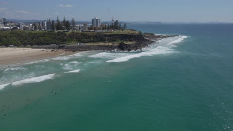 Panoramic-View-Of-The-Surfers-At-Duranbah-Beach-With-Point-Danger-Lookout-At-The-Backdrop-In-Gold-Coast,-Australia