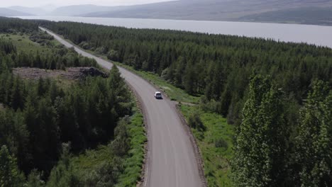 Vehicle-travels-on-gravel-road-in-national-forest-of-Iceland,-Hallormsstaður