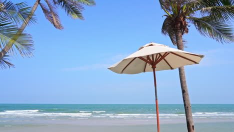 Ein-Weißer-Sonnenschirm-Am-Tropischen-Exotischen-Strand-Mit-Palmen-Und-Meer-Im-Hintergrund