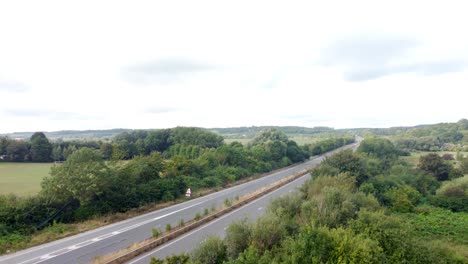 Aerial-Rising-Behind-Trees-To-Reveal-Empty-A2-Dual-Carriageway