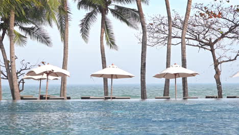 Tropische-Strandlounge-Mit-Swimmingpool,-Sonnenschirmreihe-Mit-Liegestühlen-Neben-Dem-Meer-Oder-Ozean