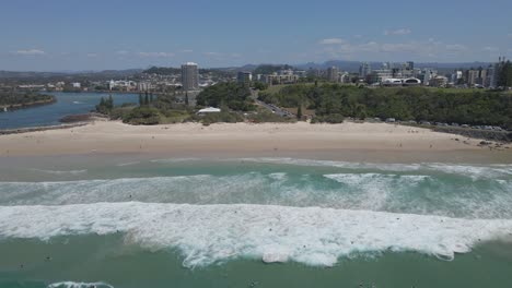 People-Walking-At-The-Sandy-Seashore-And-Surfers-Enjoying-The-Ocean-Waves-In-Letitia-Beach-In-Gold-Coast,-Australia