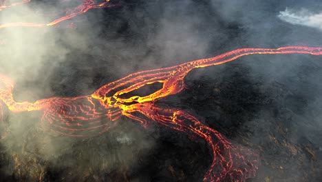 Lava-flowing-at-the-eruption-site-in-Iceland,-while-smoke-billows-from-the-crater