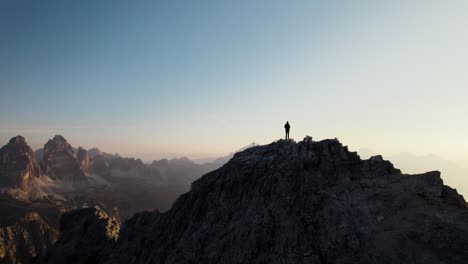 Eine-Person-Steht-Auf-Einem-Berggipfel-In-Den-Dolomiten-Und-Beobachtet-Den-Sonnenaufgang