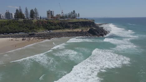Touristen,-Die-Auf-Ihren-Sufboards-Am-Strand-Von-Duranbah-Mit-Blick-Auf-Point-Danger-Lookout-In-Gold-Coast,-Australien,-Schweben