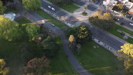 Aerial-shot-of-car-driving-on-path-of-Sarmiento-Park-in-Buenos-Aires-during-sunset---Tracking-shot---Beautiful-colorful-treetops-during-autumn-day
