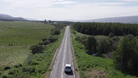 Car-driving-on-rural-road-in-Iceland-with-green-landscape,-aerial