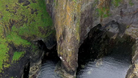 Downward-angle-drone-shot-of-Whaligoe-Haven-and-the-rocky-250ft-cliffs-overlooking-the-north-sea-in-Scotland