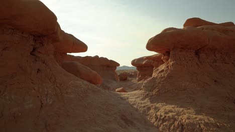 Gorgeous-stunning-tilt-up-shot-of-the-beautiful-Goblin-Valley-Utah-State-Park-mushroom-rock-formations-with-space-to-walk-between-them-on-a-week-on-a-warm-sunny-summer-day