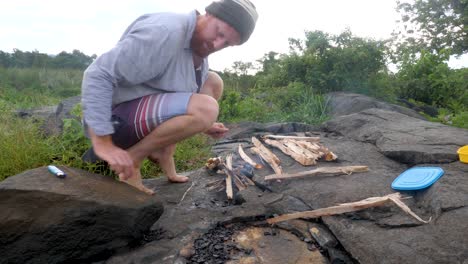 Ein-Mann,-Der-Im-Ländlichen-Afrika-Am-Ufer-Des-Viktoriasees-Ein-Lagerfeuer-Entfacht