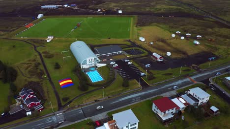 Vista-Aérea-De-Un-Automóvil-Conduciendo-En-La-Pequeña-Ciudad-De-Vogar-En-El-Suroeste-De-Islandia