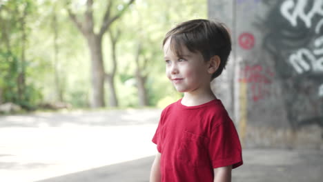 Camera-moving-right-to-left-to-take-a-shot-of-a-young-little-boy-in-a-red-T-shirt-looking-away-smiling-in-joy