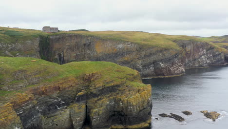 Cinematic-drone-shot-of-Whaligoe-Haven,-the-250ft-cliffs-and-rock-walls-overlooking-the-north-sea-in-Scotland