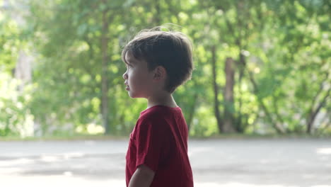 Slow-motion-video-of-a-young-little-boy-in-a-red-T-shirt-walking-in-woods