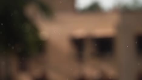 Rain-drops-falling-on-a-blurred-out-of-focus-old-village-background
