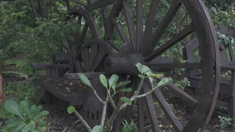 Close-up-tilt-shot-of-an-old-wagon-wheel-that-has-been-creatively-repurposed-and-made-into-a-park-bench-in-a-forest