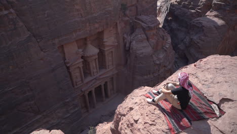 Man-Sitting-on-Cliff-Lookout-Above-Petra-Temple,-Jordan