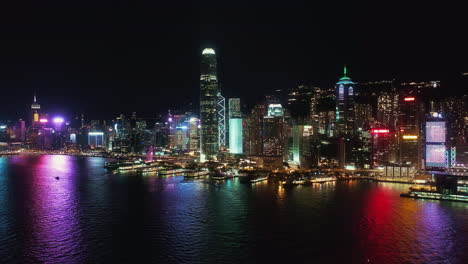 Hong-Kong-night-aerial-view-of-Hong-Kong-island,-boats-sailing-on-Victoria-Harbour