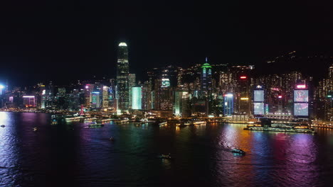 Hong-Kong-night-aerial-view-of-Hong-Kong-island,-boats-sailing-on-Victoria-Harbour