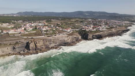 Aerial-view-of-Azenhas-do-Mar,-small-township-along-the-wild-Portuguese-coastline-facing-Atlantic-Ocean