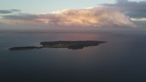 Eine-Entfernte-Drohnenaufnahme-Einer-Insel-Bei-Sonnenuntergang-Mit-Farbenfrohen-Wolken-Darüber