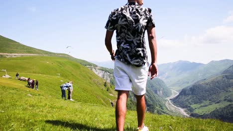 Hombre-Casual-Caminando-Por-La-Cima-De-Una-Colina-En-Kazbegi-Mirando-Al-Suelo-Del-Valle