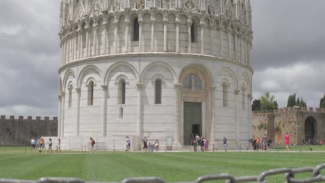 Tilt-up-from-a-Do-Not-Walk-On-Grass-sign-to-reveal-the-popular-tourist-destination-of-the-Pisa-Baptistery-in-Italy