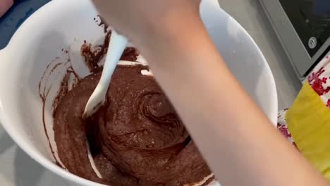Manos-Pequeñas-Revolviendo-La-Masa-De-Pastel-De-Chocolate-En-Un-Tazón-Grande-Usando-Una-Espátula
