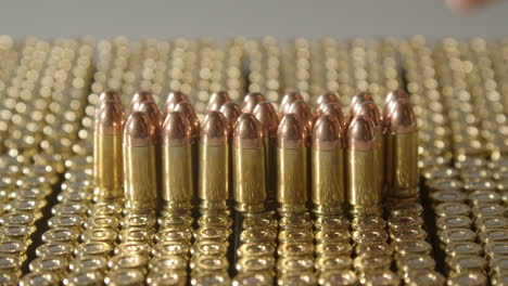 Hand-placing-single-9-millimeter-bullet-on-a-large-collection-of-ammunition