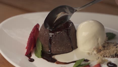 Hand-using-spoon-to-cut-delicious-chocolate-volcano-lava-dessert