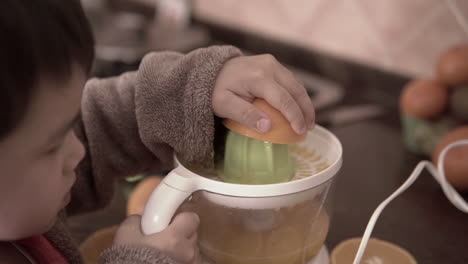 Push-in-shot-of-a-kid-squeezing-oranges-and-making-orange-juice-with-an-electric-squeezer
