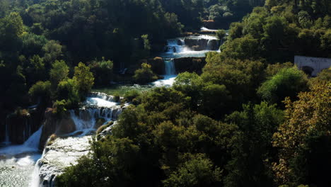 Sunlit-Waters-Of-Skradinski-Buk-Waterfall-Along-Krka-River-Surrounded-With-Dense-Trees-During-Summer