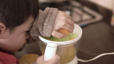 Asian-kid-making-natural-fresh-squeezed-orange-juice-by-himself
