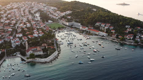 Luftaufnahme-Von-Booten,-Die-Im-Ruhigen-Ozean-Schwimmen,-Mit-Franziskanerkloster-Und-Küstenstadt-Auf-Der-Insel-Hvar,-Kroatien